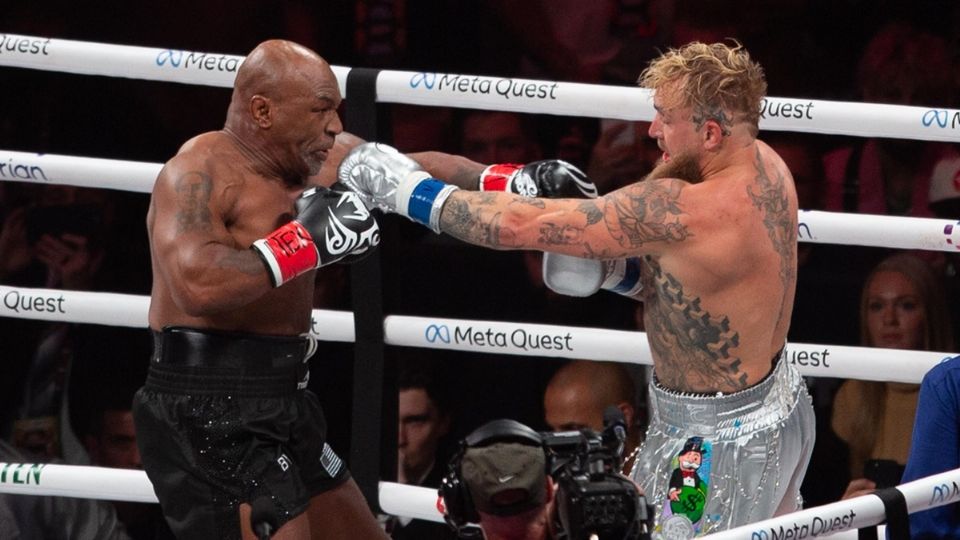 Mike Tyson (izq.) y Jake Paul intercambian golpes durante su pelea.